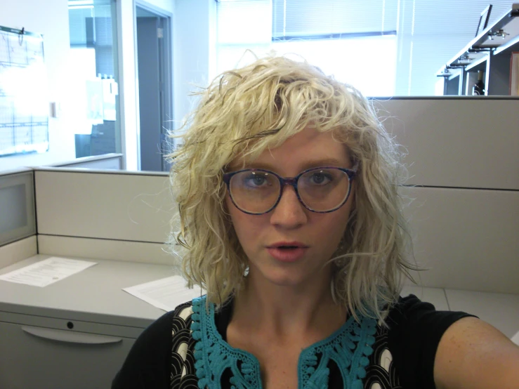 a blond woman in glasses making a funny face at the camera