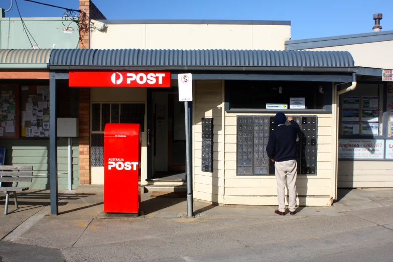 a man standing outside of a post office in the city