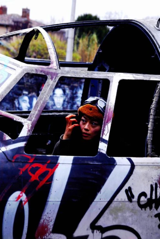 man sitting in an old aircraft with graffiti on the side