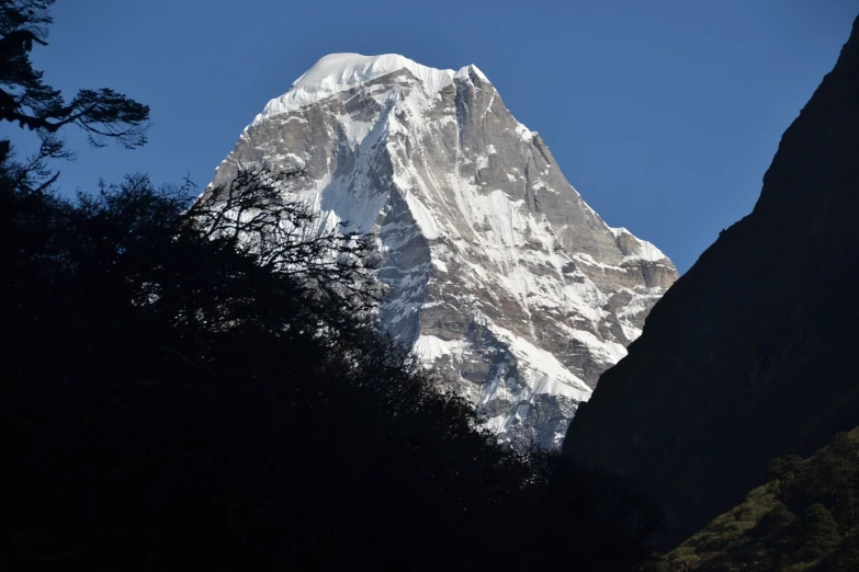 the peak of a snow covered mountain with trees below it