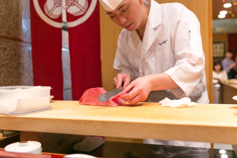 a chef is  meat on a board in the kitchen