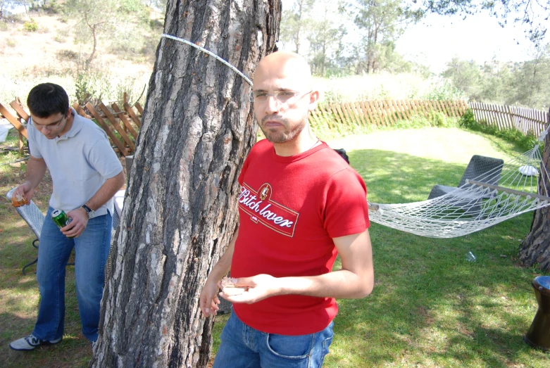 a man holding soing in his hand standing next to a tree