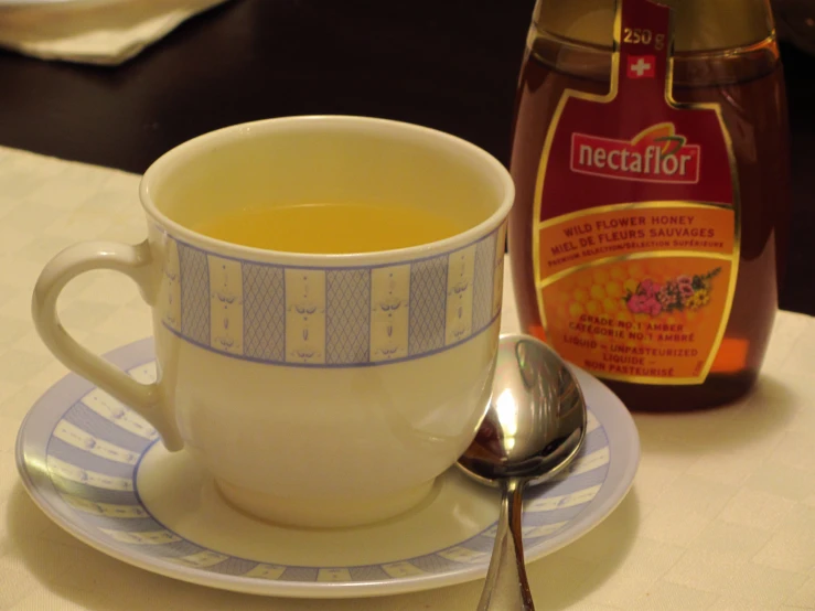 a cup of tea sits on a saucer next to a jar of honey