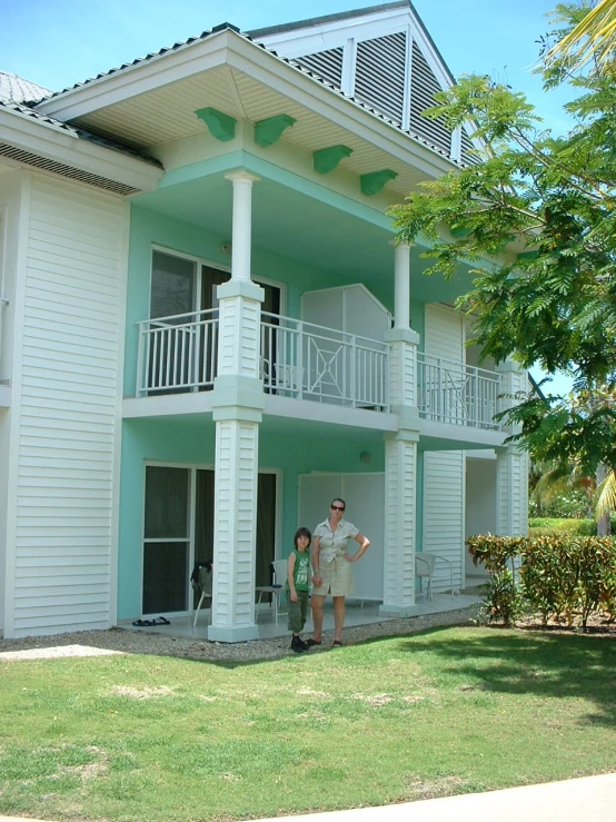 two people standing in front of a house with green lawn