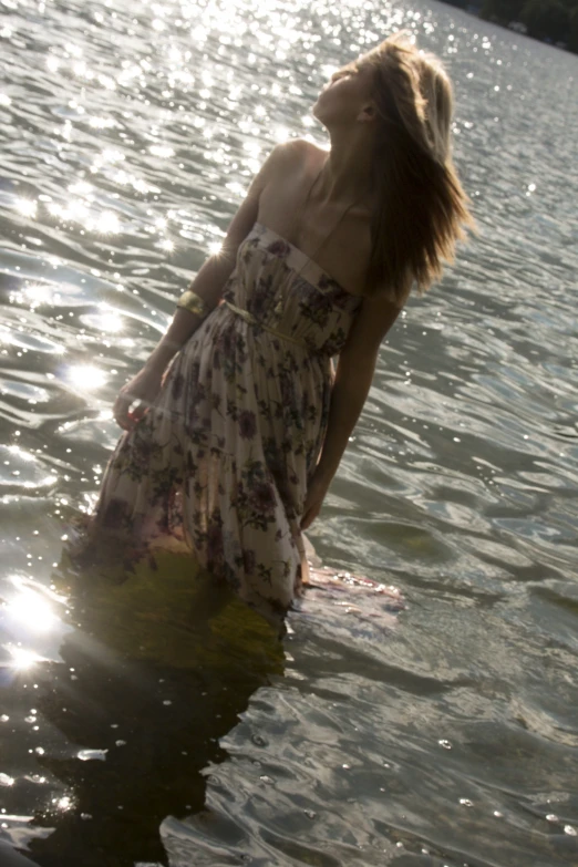 woman floating in water wearing dress and holding onto surfboard