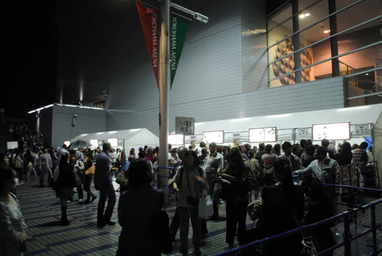 people stand near a building that contains large banners and flags