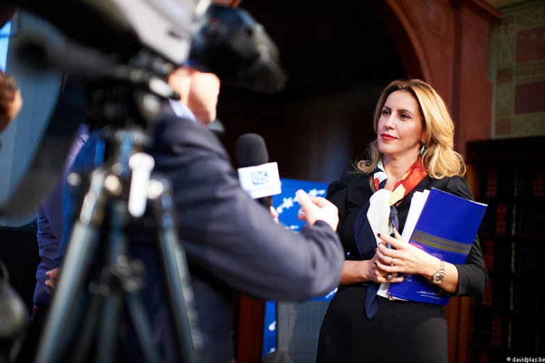 a person talking to a camera and holding papers