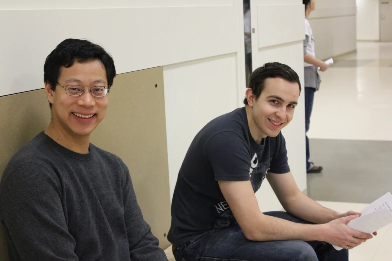 two men sit on the ground in a hallway