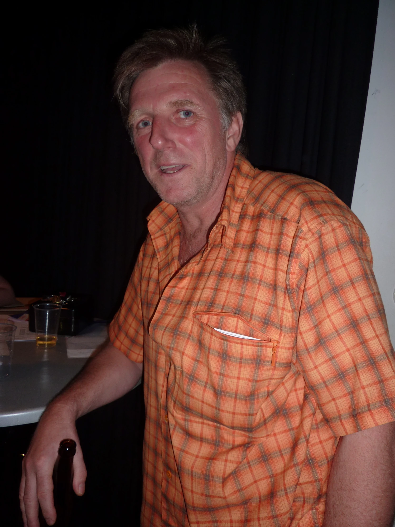 man in plaid shirt at table smiling at the camera