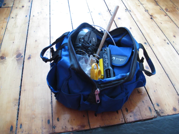 a blue backpack filled with items sitting on top of a wooden table