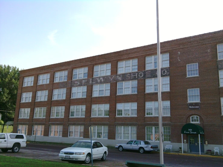 the large building is next to several white cars