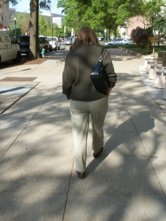 a lady walking down the sidewalk while carrying a purse