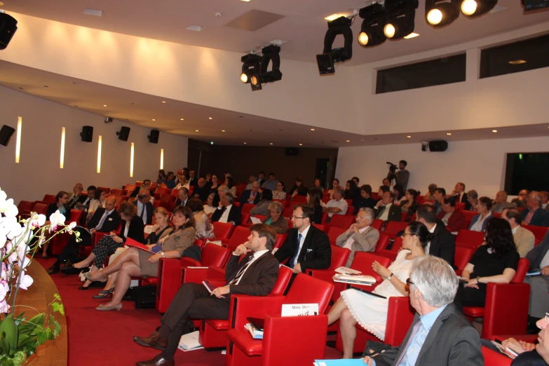 people in auditorium looking over a podium with speakers