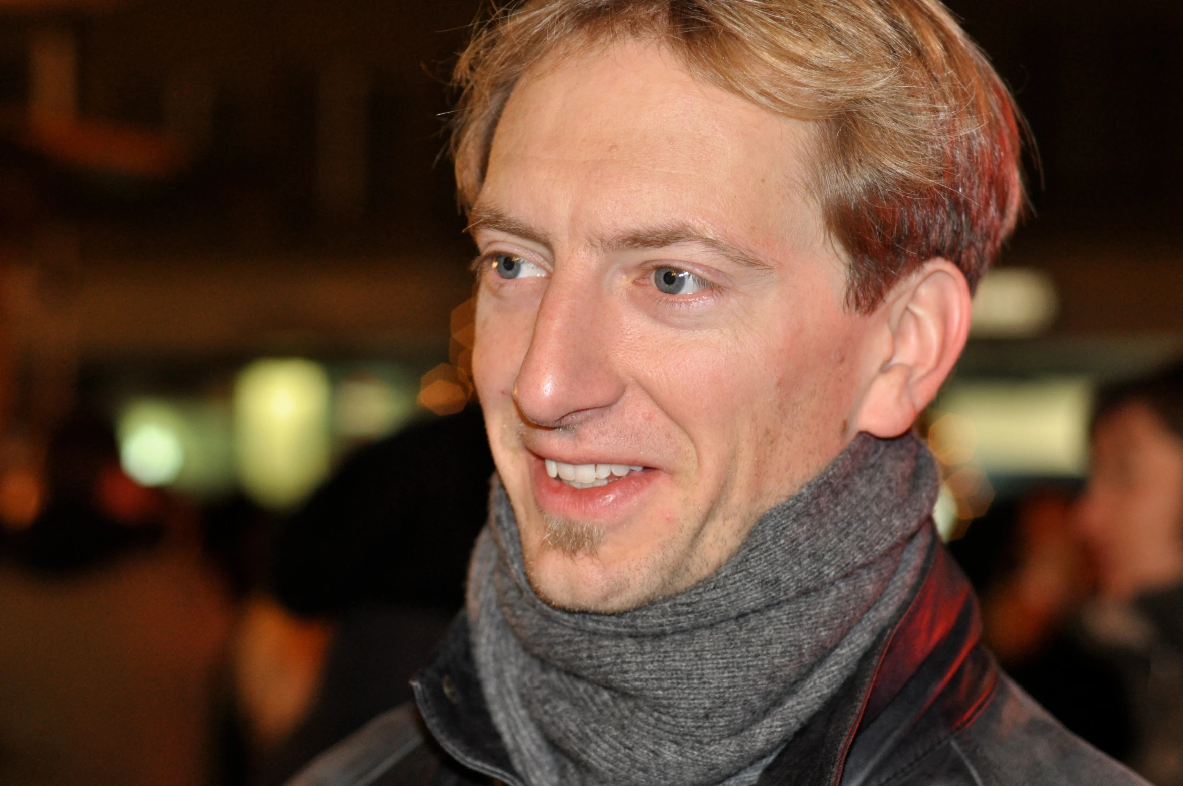 a man with long hair and a beard wearing a gray scarf