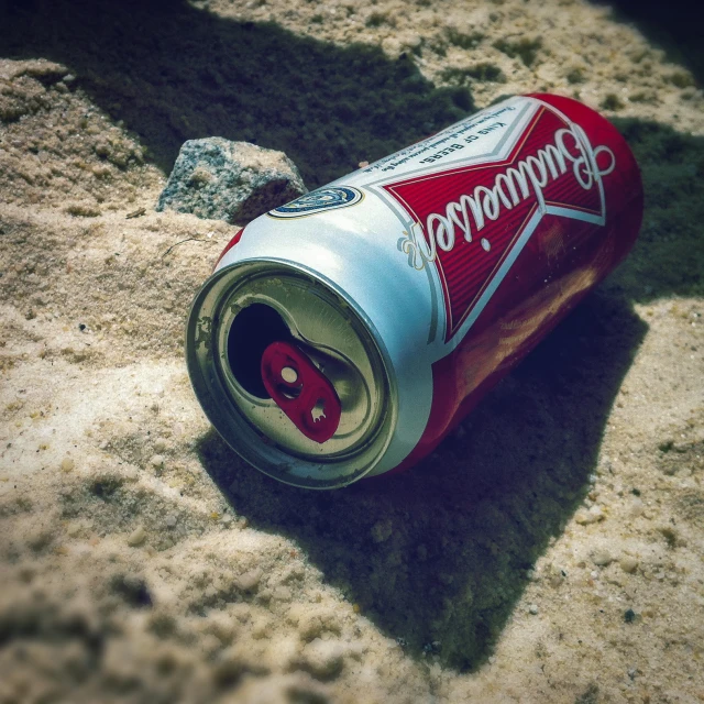 an open can of soda is shown in the sand