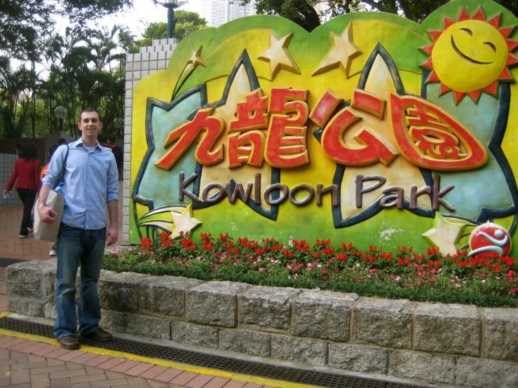 a man stands in front of a colorful sign