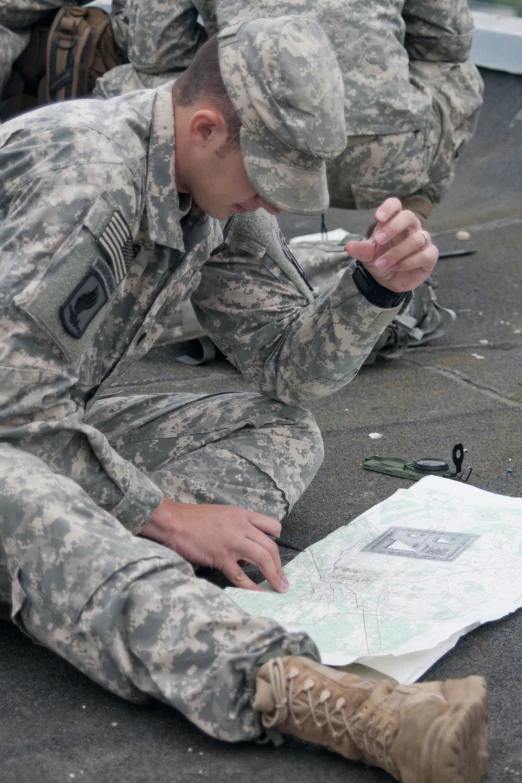 two men dressed in camouflage sit on the ground