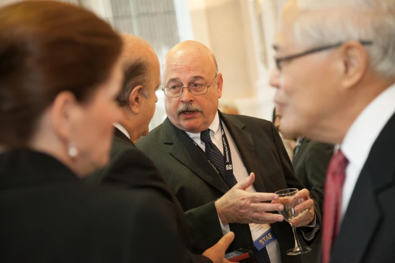 several people are standing talking while wearing suits