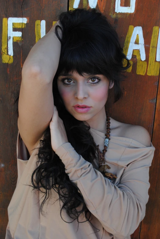 a woman is leaning up against a wooden wall with her hands on her head