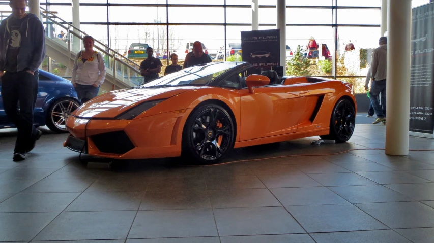 a man is looking at an orange sports car