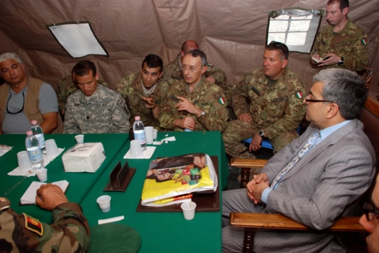 men in military uniform sit at a table to discuss