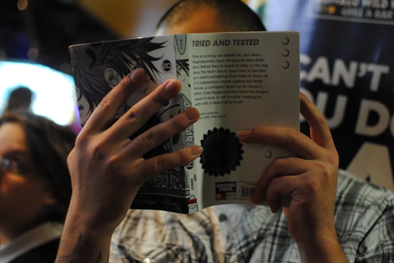 a man reading an open book in front of a crowd