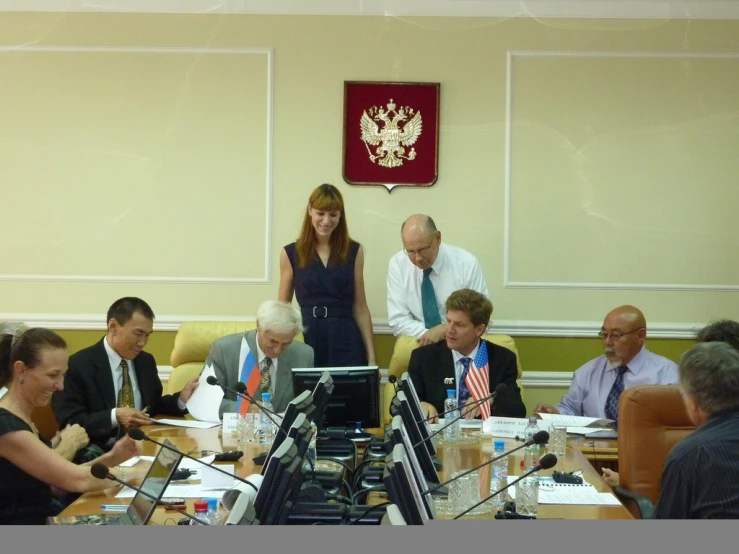 people sit around tables using their laptops during a meeting