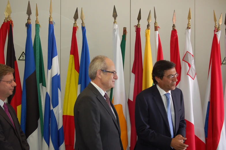 four men standing behind flags in front of each other