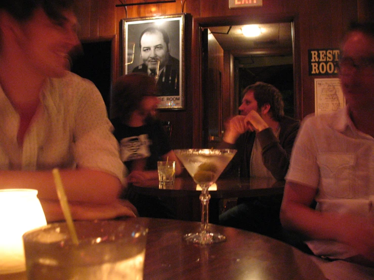 three people sitting at a table with a drink