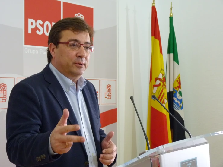 a man in glasses speaking at a podium