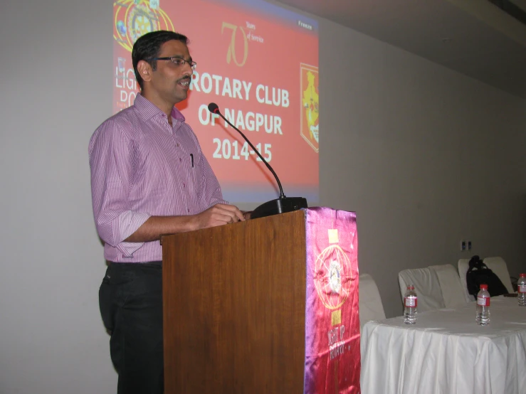 man speaking into a podium at rotary club