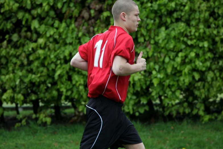 a soccer player in a red shirt running towards a green soccer field
