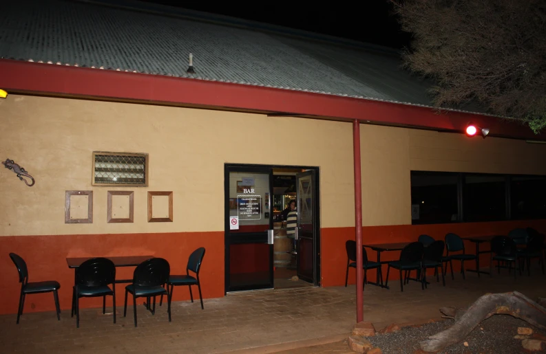 an empty table outside of a restaurant with a red light