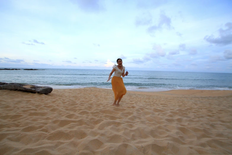 a man stands in the sand as another man plays with a frisbee