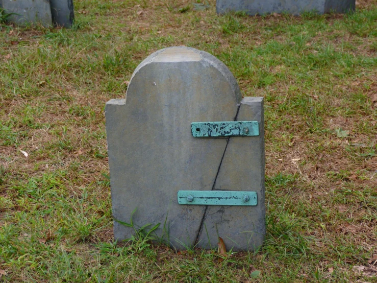 a grave with two green keys on it in a field