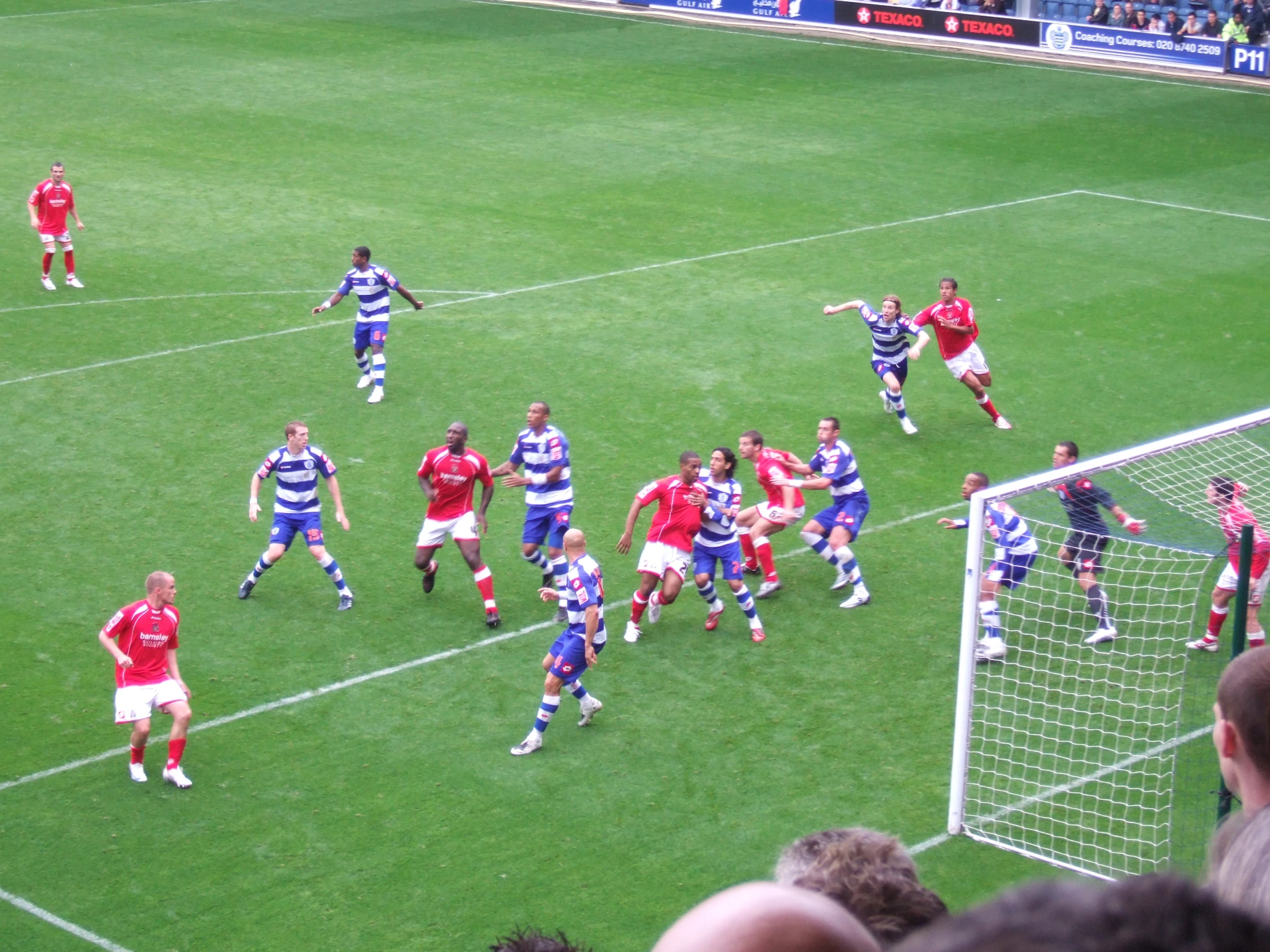 soccer players in red and blue uniforms playing on a grass field