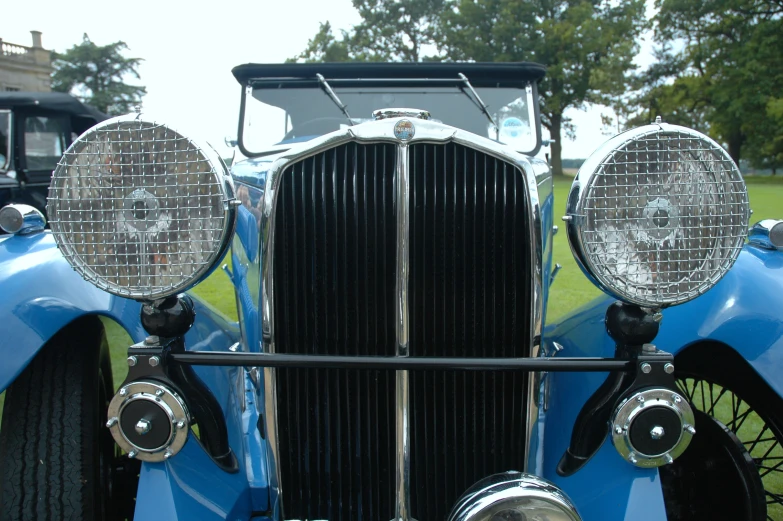 an old blue car is parked in the grass