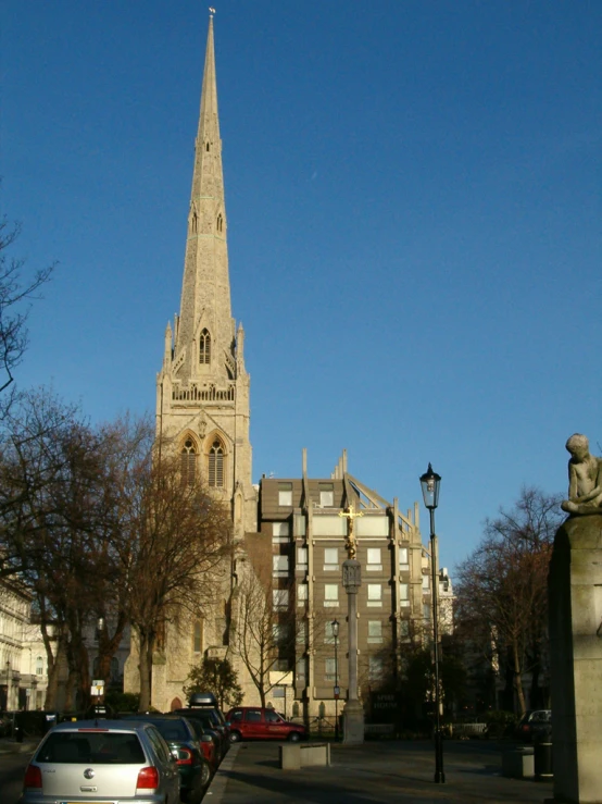 a cathedral with a clock tower and cars parked along side