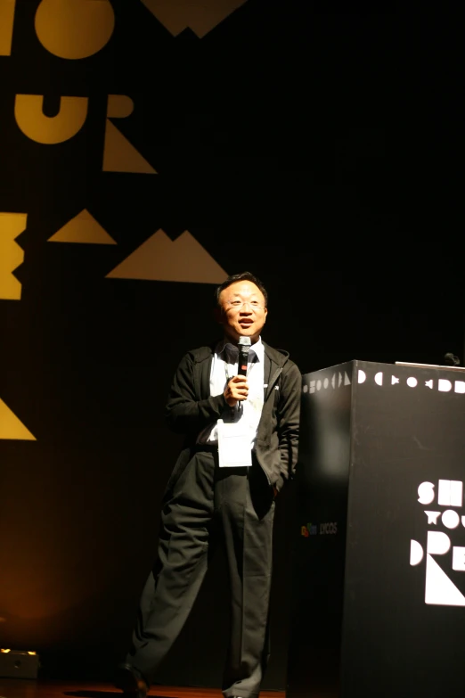 a man wearing a suit holding a microphone at a podium