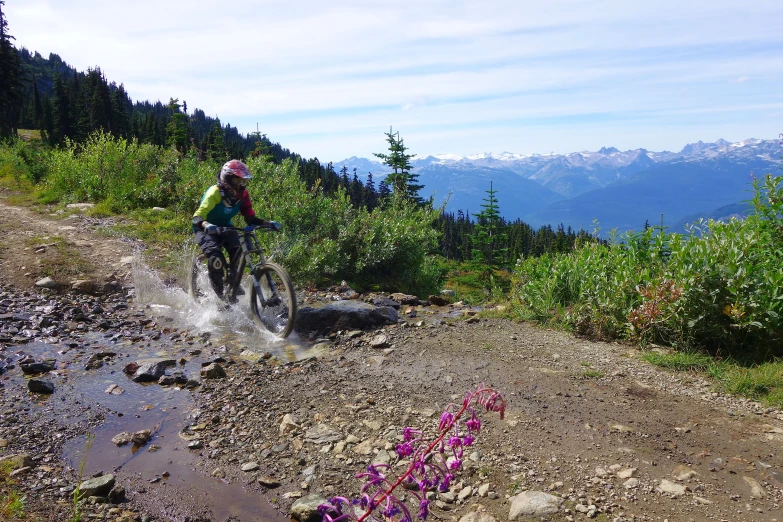 a mountain biker wearing yellow clothes goes through the mud