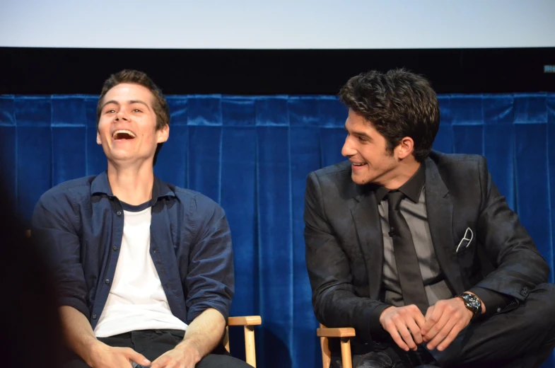 two young men laughing as they sit in chairs