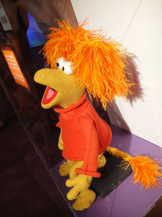 a stuffed toy is wearing an orange jacket