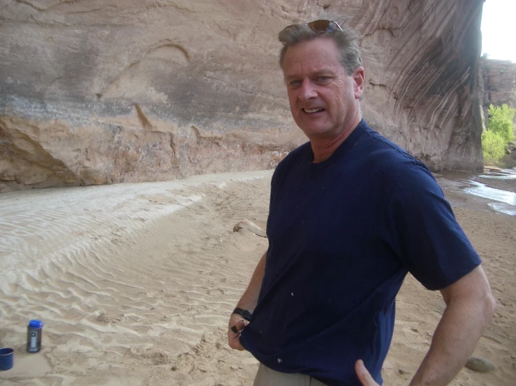 the man in the blue shirt stands near a body of water