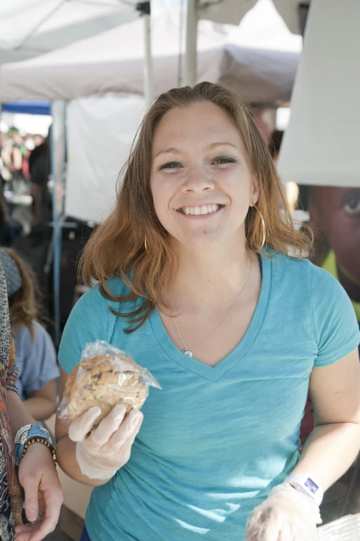 woman holding food items at outdoor market and smiling