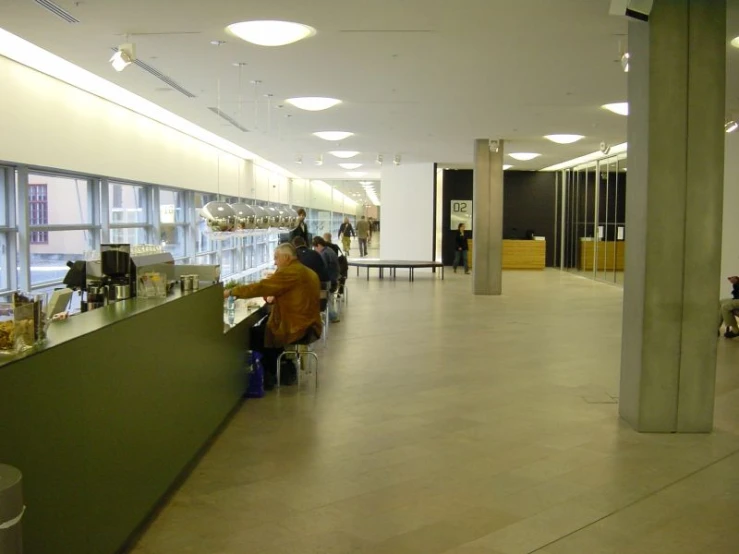 people sitting in a room next to a wall of windows