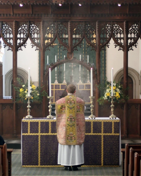 a priest in a yellow jacket standing at the alter