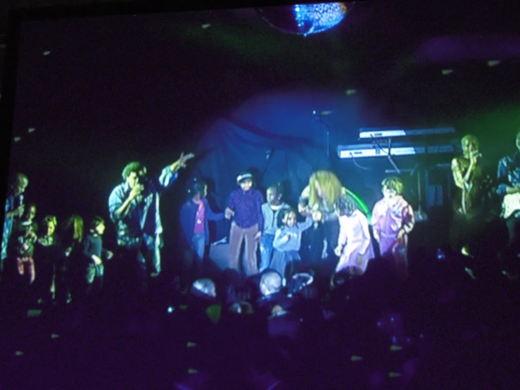 a group of people are on stage and some are on a phone