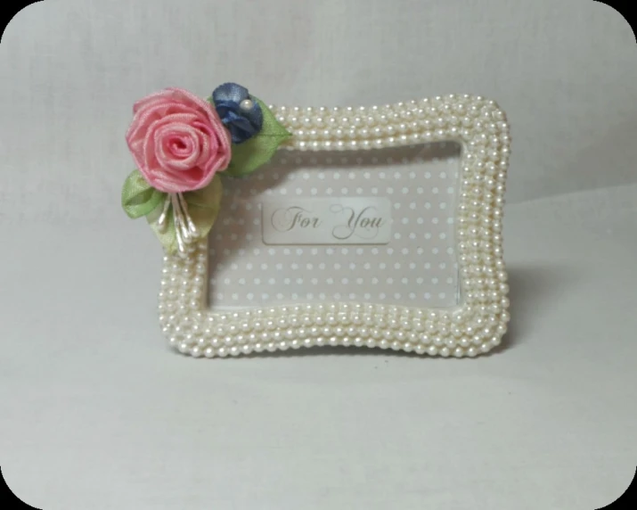 a white and pink flower frame with a name tag