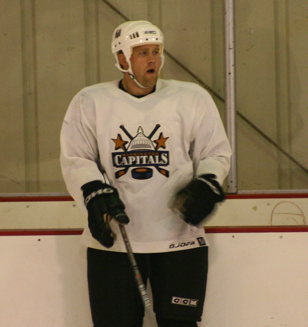 the hockey player is holding his hockey sticks while standing in front of the net