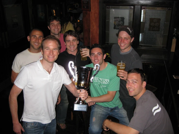 some guys holding up a glass and posing for the camera